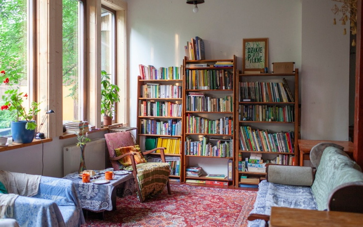 Przytulny pokój z regałem pełnym książek i roślinami.
