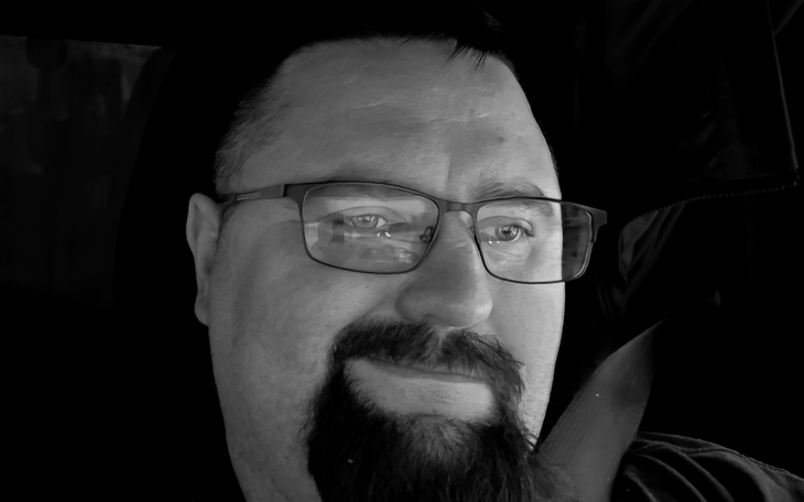 Mężczyzna z okularami uśmiechający się do kamery.