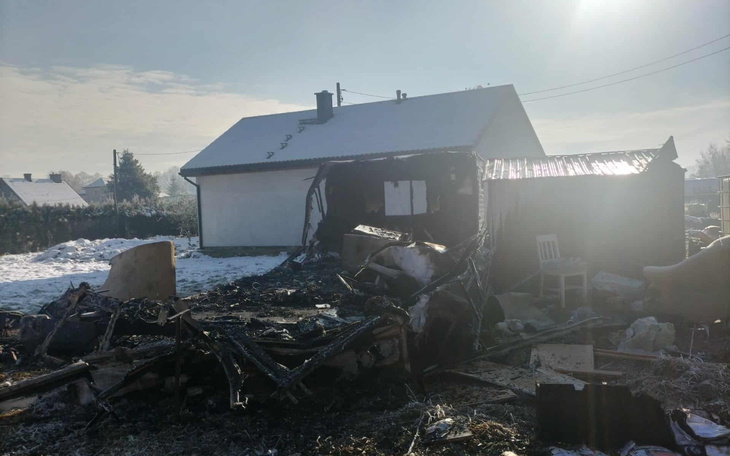 Zniszczony budynek po pożarze, z widocznymi zgliszczami i śniegiem w tle.