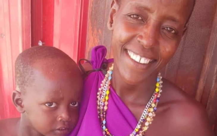 Uśmiechnięta kobieta z dzieckiem, ubrana w tradycyjne stroje.