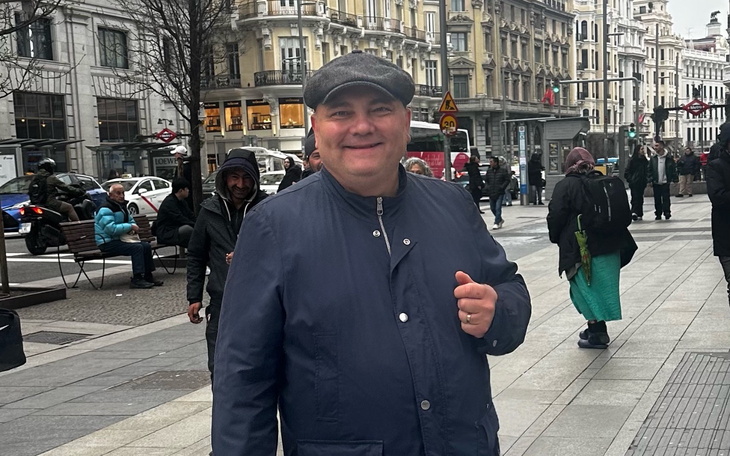 Mężczyzna w kapeluszu na ulicy, z uśmiechem na twarzy.