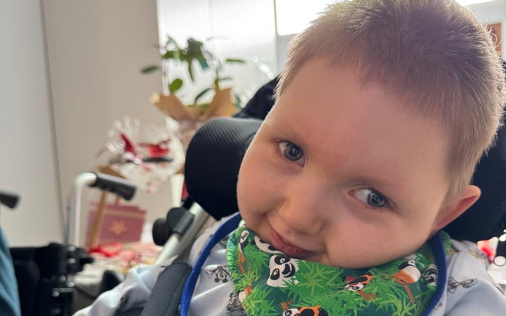 Chłopiec na wózku inwalidzkim, uśmiechający się do kamery.