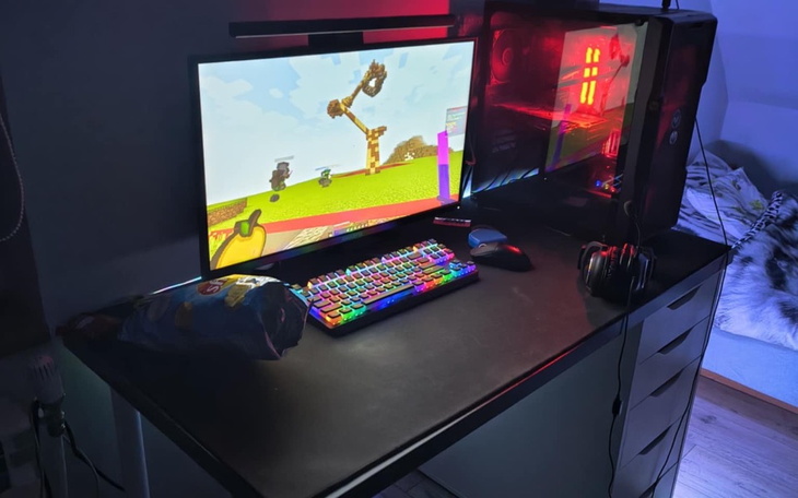 Biurko z komputerem, kolorową klawiaturą i słuchawkami.