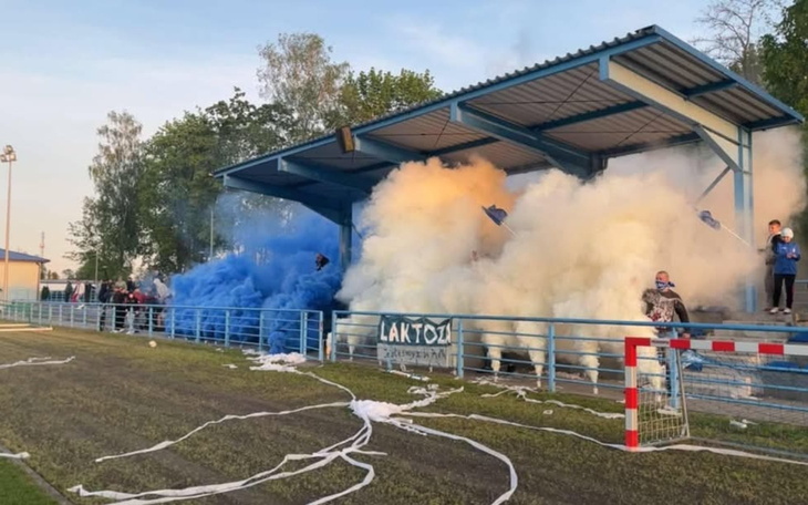 Fani na stadionie, otoczeni dymem w niebiesko-białych barwach.
