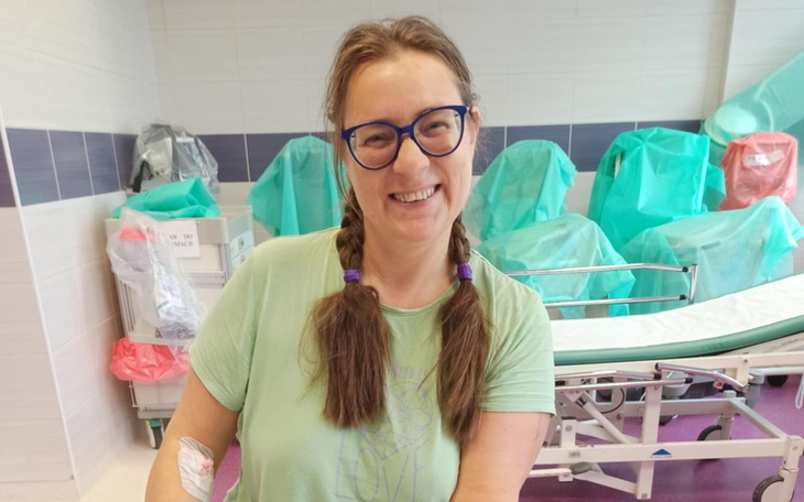 Uśmiechnięta kobieta w szpitalu, z opatrunkiem na ręce.