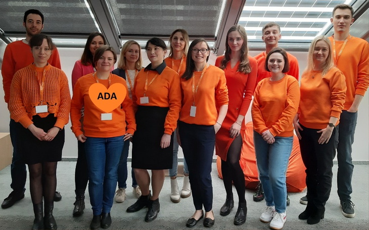 Zespół ludzi w pomarańczowych ubraniach, pozujący do zdjęcia.