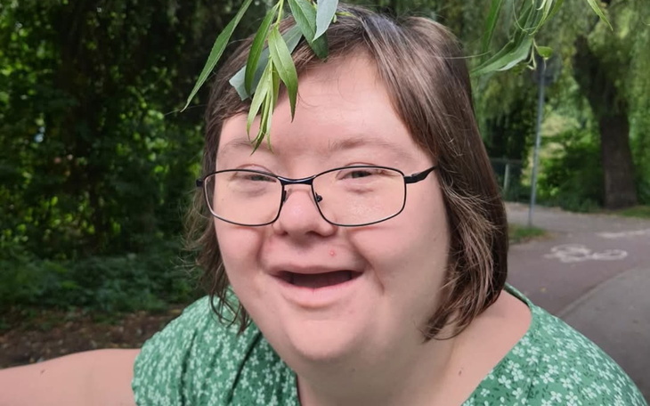 Uśmiechnięta kobieta z okularami, z gałązką na głowie.