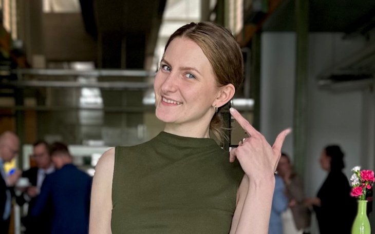 Młoda kobieta uśmiechająca się i wskazująca na siebie.