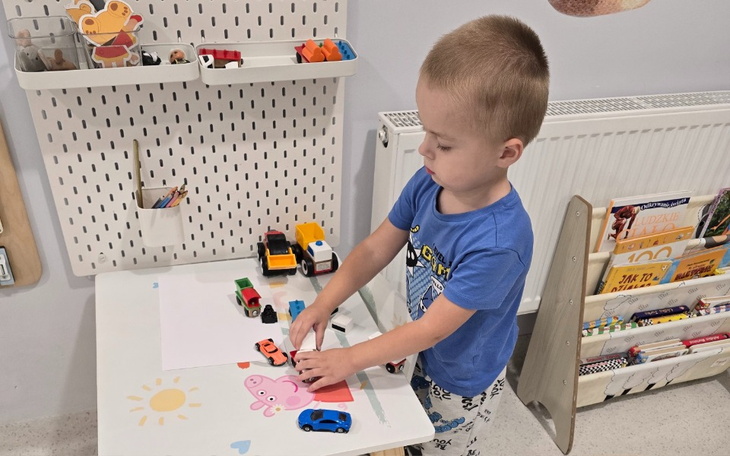 Chłopiec bawi się samochodzikami przy stole.