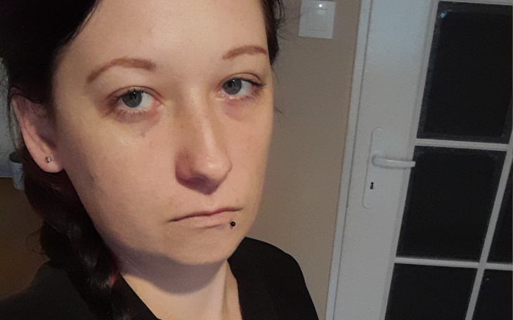 Portret osoby z wyraźnym wyrazem twarzy w domowym otoczeniu.