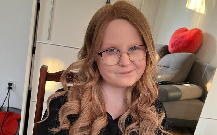 Uśmiechnięta dziewczynka z długimi włosami i okularami.