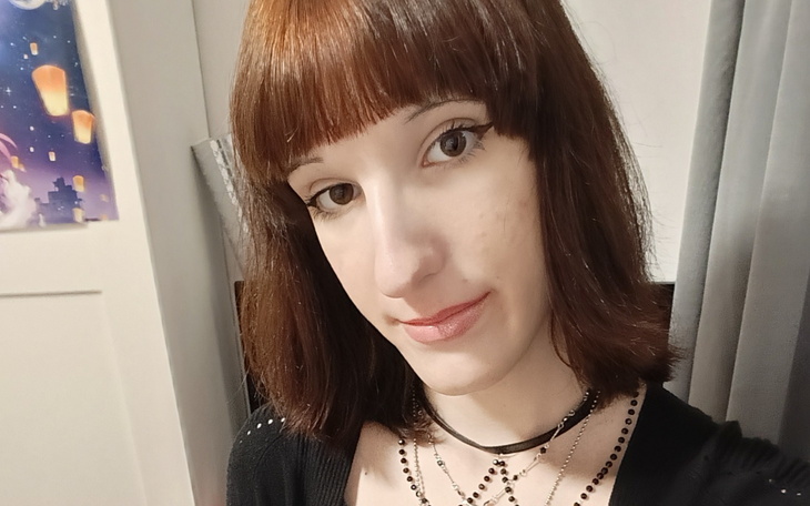 Młoda kobieta z krótkimi włosami, uśmiechająca się do kamery.