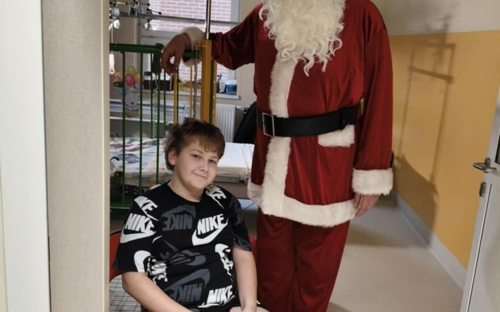 Chłopiec siedzący obok Świętego Mikołaja w szpitalu.
