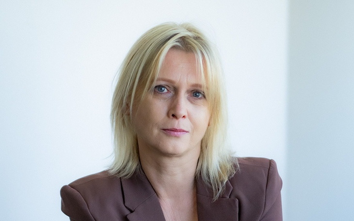 Portret kobiety z blond włosami, w biurowym otoczeniu.