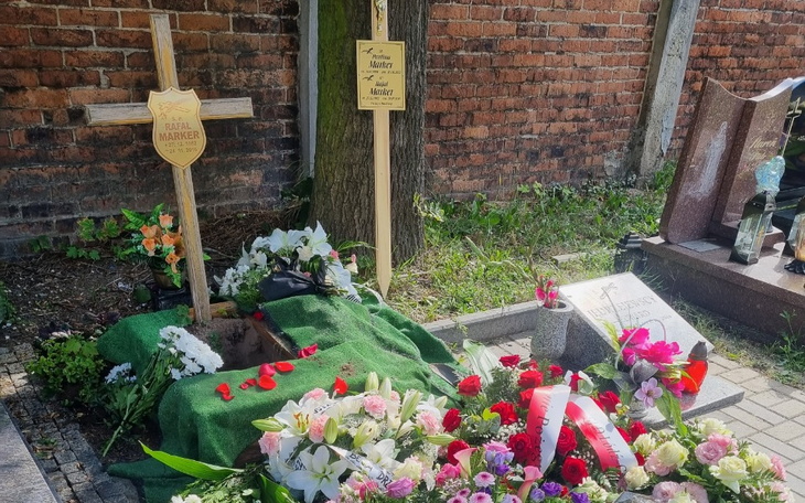 Grób z kwiatami i znakiem pamięci na cmentarzu.