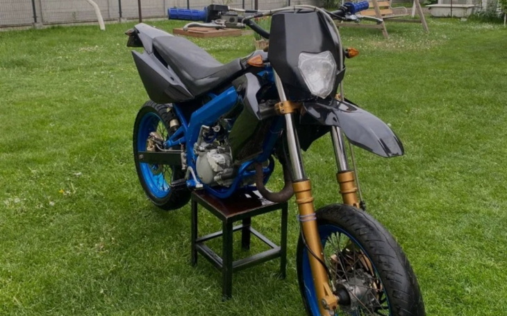 Motocykl na trawie, z niebieskimi akcentami i czarną owiewką.