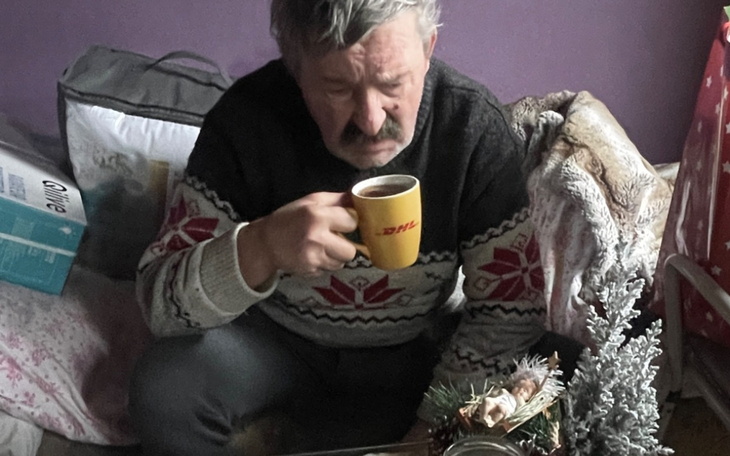 Mężczyzna pijący kawę, siedzący w przytulnym wnętrzu.