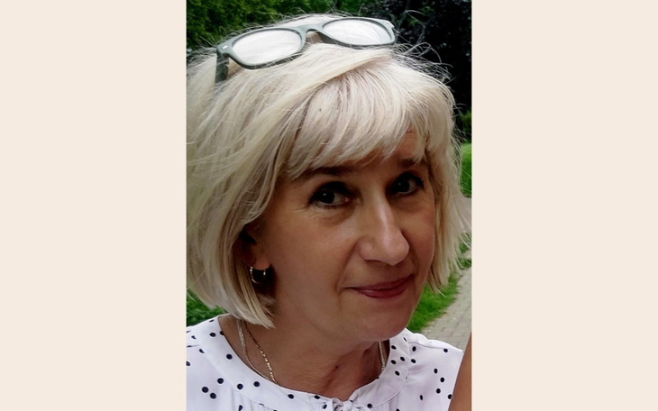 Portret kobiety z krótkimi włosami i okularami na głowie.