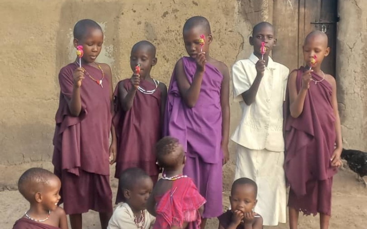 Grupa dzieci w tradycyjnych strojach, trzymających lizaki.