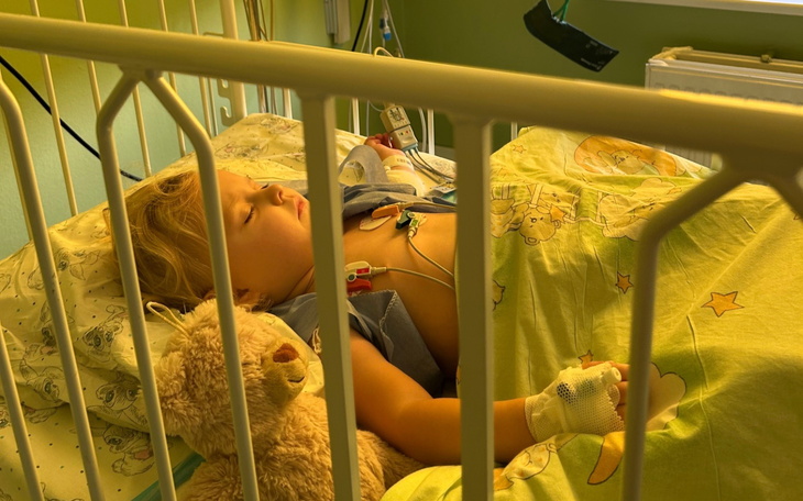 Chłopiec w szpitalnym łóżku, trzymający pluszowego misia.