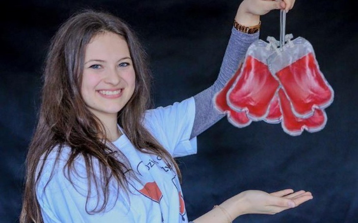 Młoda dziewczyna trzymająca woreczki z krwią, uśmiechająca się.