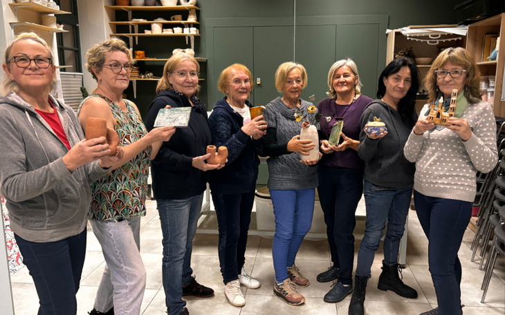 Grupa kobiet prezentujących swoje rękodzieło w warsztatach artystycznych.