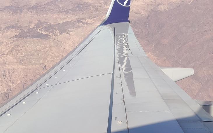 Widok z okna samolotu na górzysty krajobraz.