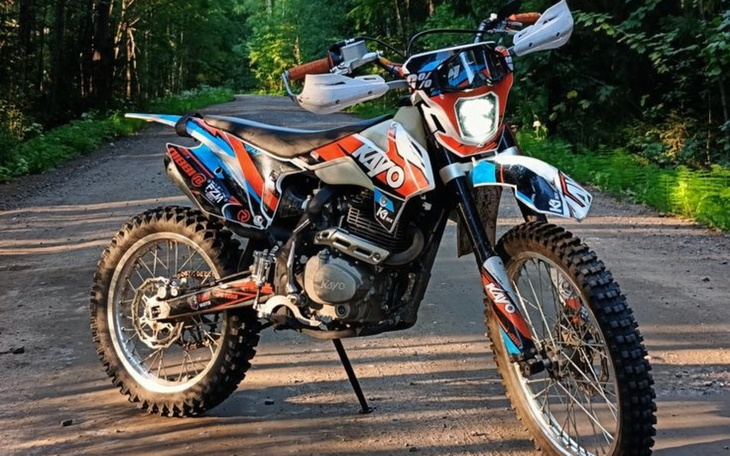 Motocykl terenowy Kayo na leśnej drodze, gotowy do jazdy.