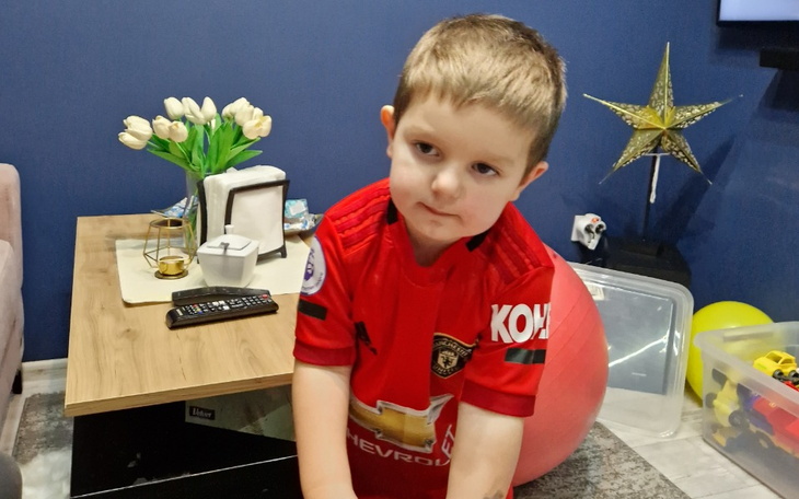 Chłopiec w czerwonym stroju, bawiący się w domu.