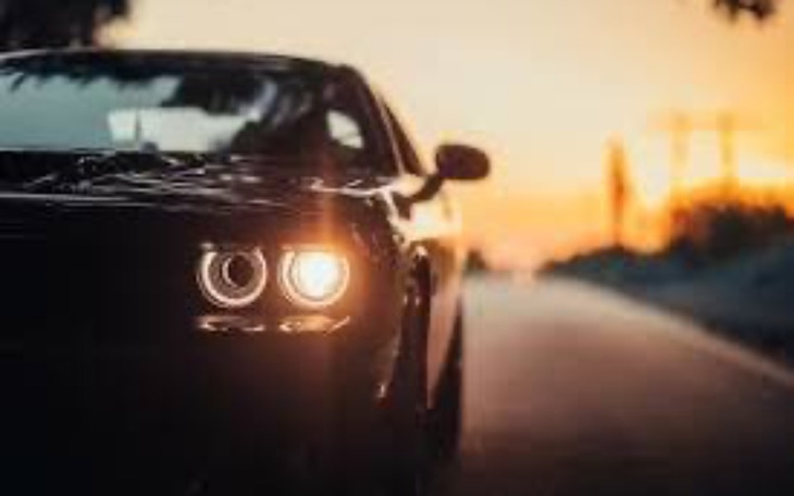 Czarny samochód na drodze przy zachodzie słońca.