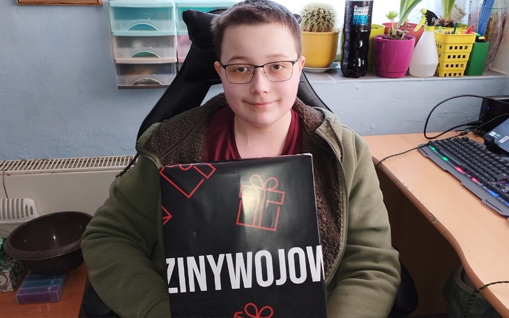 Chłopiec trzymający prezent, uśmiechający się w swoim pokoju.