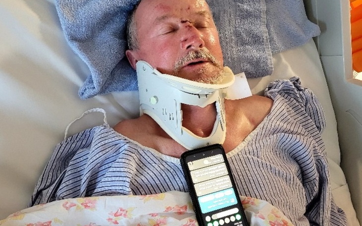 Mężczyzna w szpitalu z opatrunkiem na głowie i kołnierzem ortopedycznym.