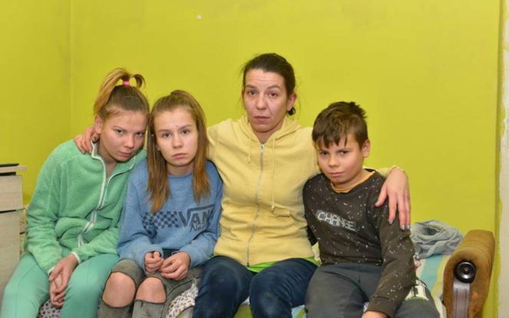 Rodzina siedząca na kanapie w jasnym pomieszczeniu.