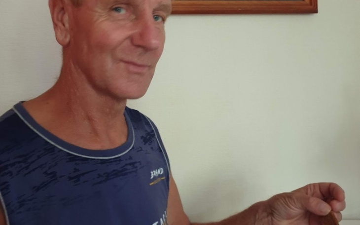 Mężczyzna uśmiechający się do kamery, trzymający coś w ręku.