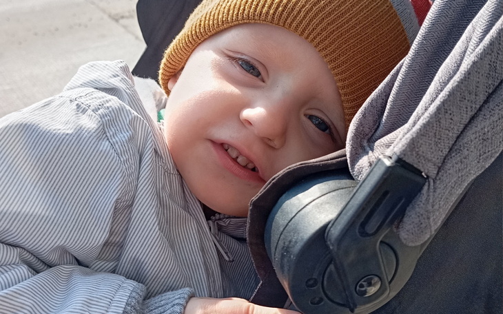 Małe dziecko w wózku, z uśmiechem na twarzy.