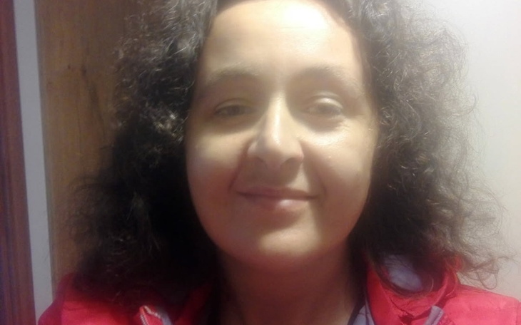 Kobieta z kręconymi włosami, uśmiechająca się do kamery.