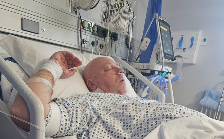 Mężczyzna w szpitalu, leżący na łóżku z podłączonymi urządzeniami.