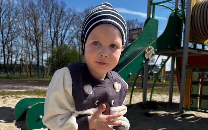 Chłopiec w czapce na placu zabaw, uśmiechający się do kamery.
