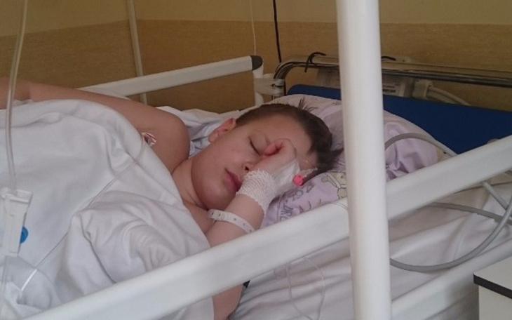 Dziecko w szpitalnym łóżku, z opatrunkiem na ręce.