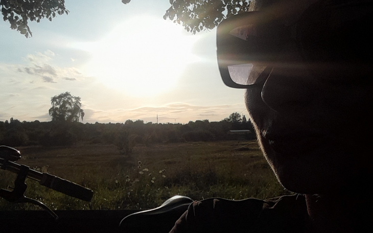 Osoba w okularach przeciwsłonecznych na tle zachodzącego słońca.