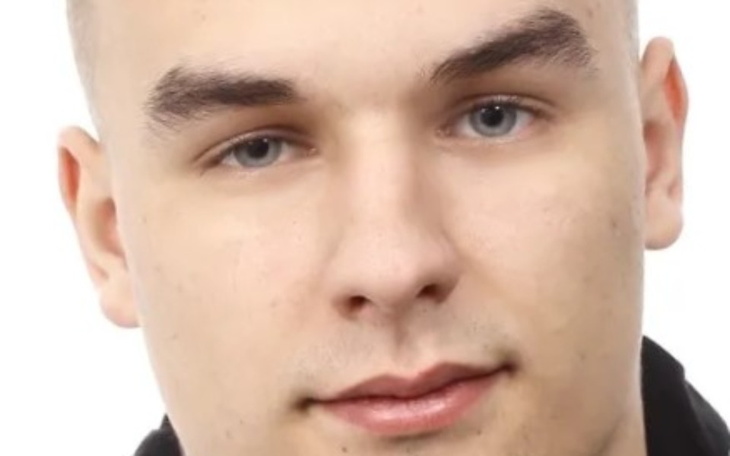 Portret mężczyzny, neutralne tło, skupiony wyraz twarzy.