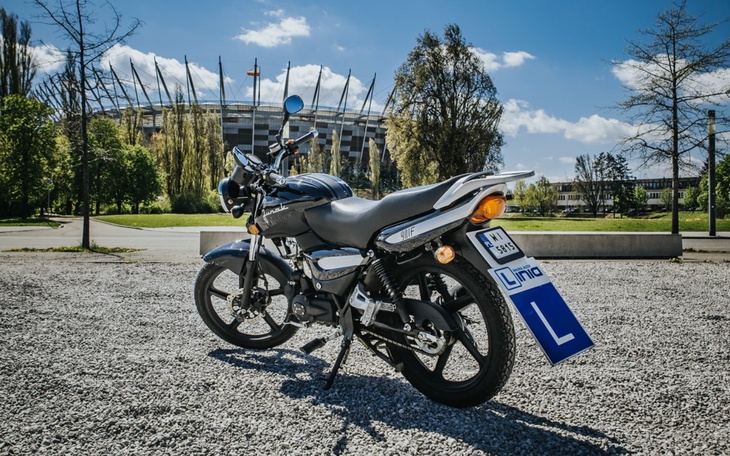 Motocykl zaparkowany na tle stadionu w słoneczny dzień.