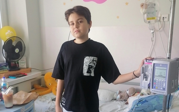 Chłopiec w szpitalu, trzymający kroplówkę obok łóżka.