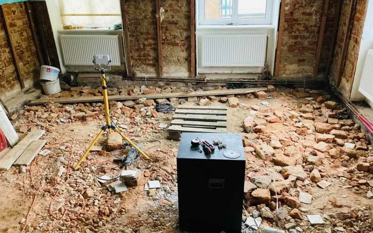Zniszczona podłoga w trakcie remontu, widoczne kamienie i narzędzia.
