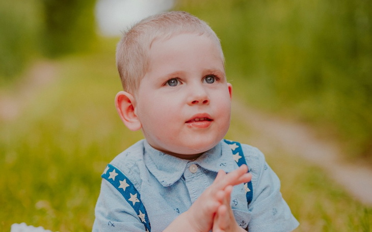 Mały chłopiec w niebieskiej koszuli, uśmiechający się.