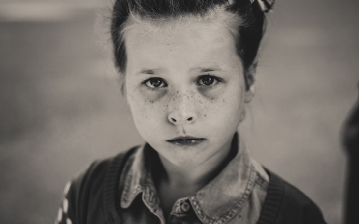 Czarno-białe zdjęcie dziewczynki z piegami, patrzącej w obiektyw.