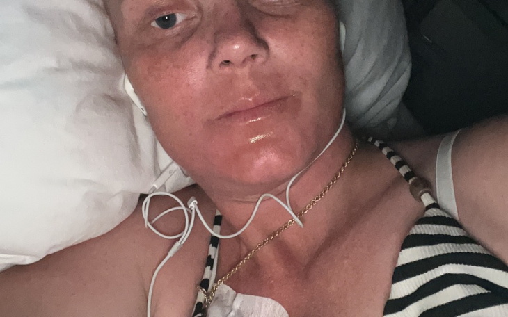 Kobieta leży w łóżku, słuchając muzyki, z widocznym monitorem medycznym.