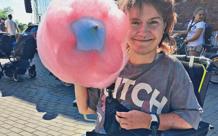 Młoda kobieta z watą cukrową, uśmiechająca się do kamery.