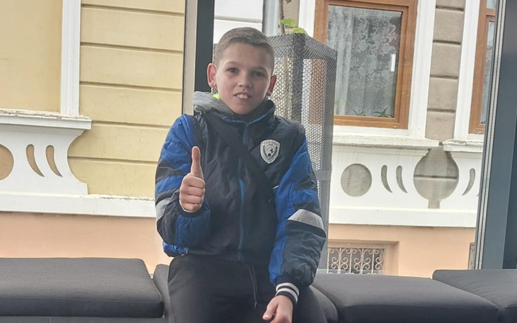 Chłopiec siedzący na kanapie z kciukiem w górę.