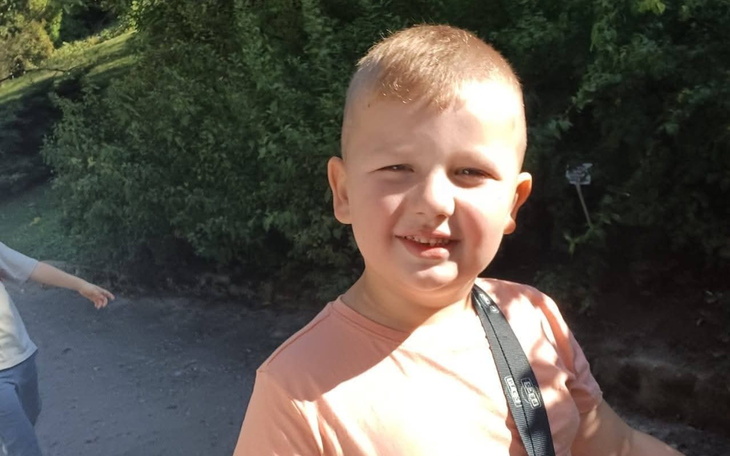 Chłopiec uśmiechający się na tle zieleni.